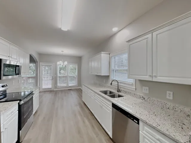 a kitchen with granite countertop a sink stainless steel appliances and cabinets
