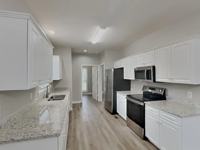 a kitchen with granite countertop a sink stainless steel appliances and cabinets