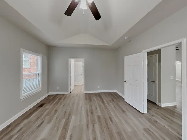 an empty room with wooden floor cabinet and windows