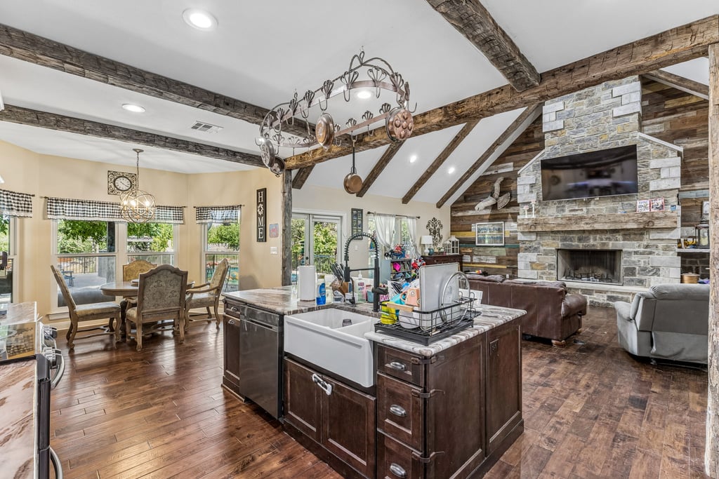 10111 Signal Hill Road Austin, TX 78737 - Photo 10 of 40 Exposed ceiling beams and a stone fireplace anchor this open living and dining area.