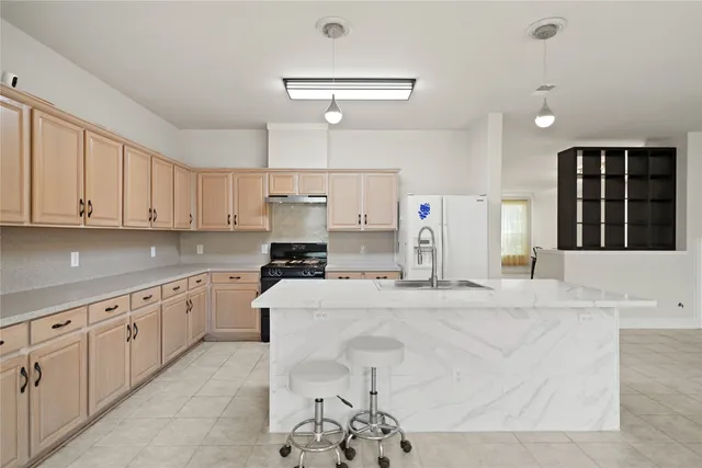 a kitchen with granite countertop a sink a stove and refrigerator