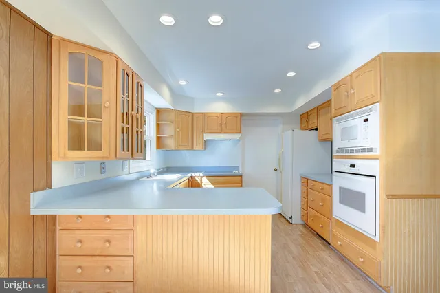 a kitchen with granite countertop wooden cabinets a sink and dishwasher next to a window