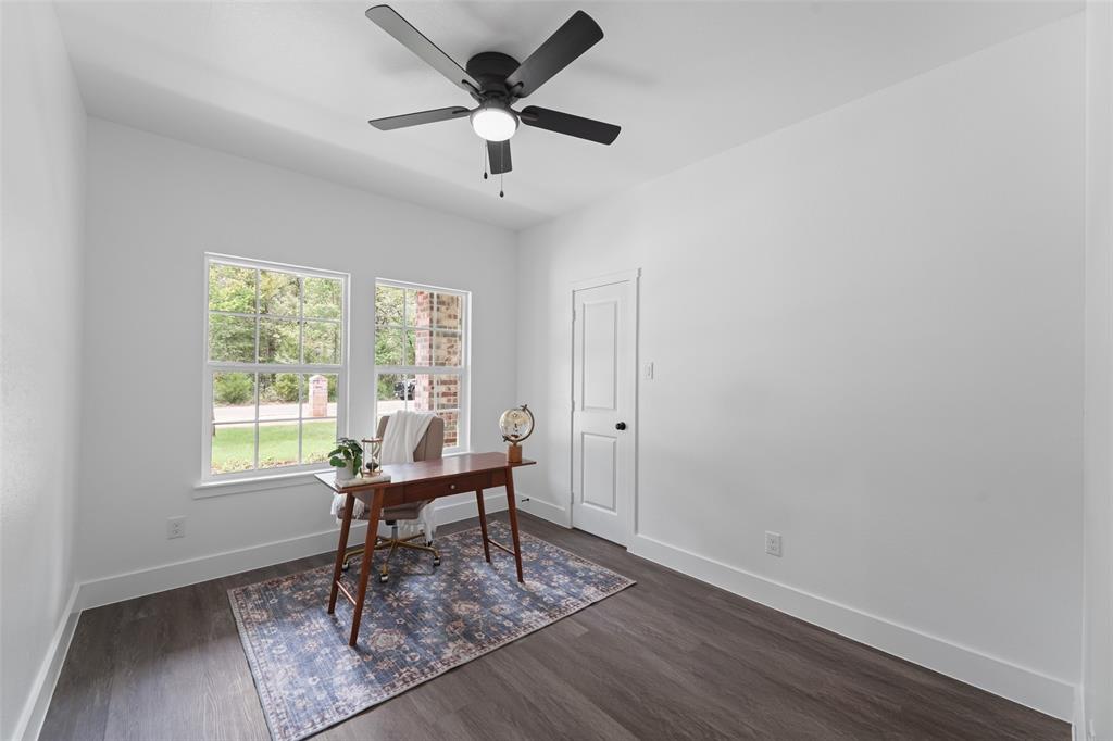 122 East Beachwood Loop Trinidad, TX 75163 - Photo 26 of 35 Bright room featuring two large windows, dark wood-finish flooring, a modern black ceiling fan with integrated lighting, a white paneled door, and crisp white walls