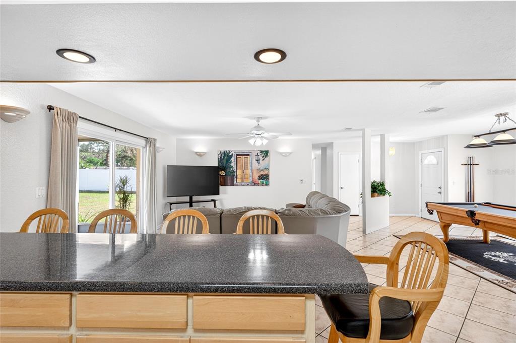 1409 Bryan Road Brandon, FL 33511 - Photo 12 of 73 a kitchen with kitchen island granite countertop a stove a sink a dining table and chairs with wooden floor