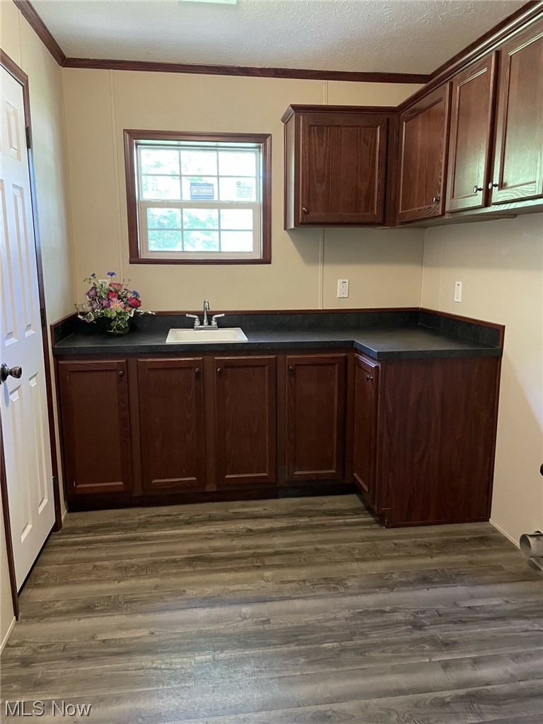 3651 Austin Road, Unit 33 Geneva, OH 44041 - Photo 4 of 4 Kitchen with a textured ceiling, hardwood flooring, dark brown cabinetry, crown molding, and dark countertops