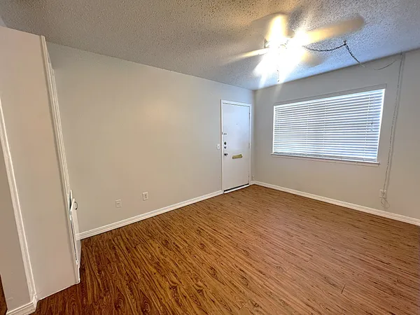 a view of an empty room with wooden floor and a window