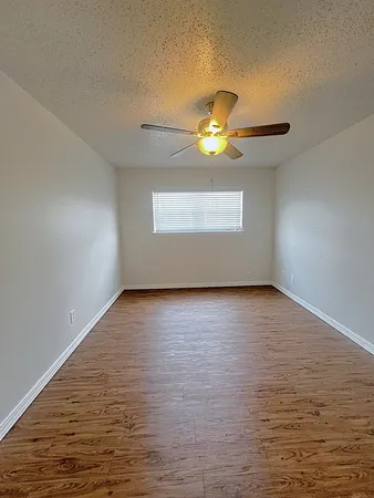 a view of an empty room with a window and wooden floor