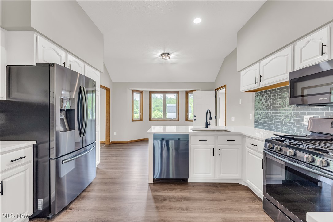 5327 Jaycox Road North Ridgeville, OH 44039 - Photo 13 of 36 Kitchen with stainless steel appliances, vaulted ceiling, a sink, a peninsula, and lvp-style floors