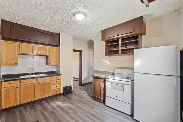 a kitchen with a sink stainless steel appliances and wooden floor