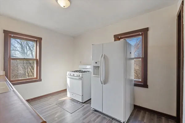 a view of a kitchen with refrigerator and wooden floor