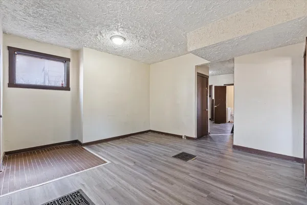 a view of an empty room with wooden floor and closet
