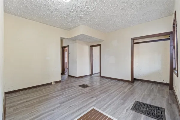 a view of an empty room with wooden floor and closet