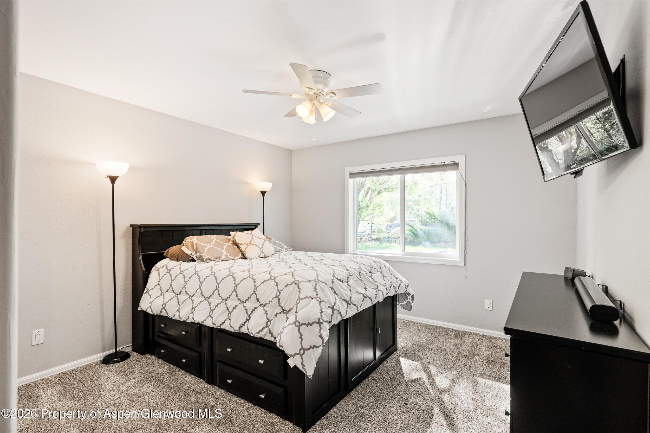 127 Cardinal Way Parachute, CO 81635 - Photo 19 of 41 a bedroom with a bed a window and a chandelier