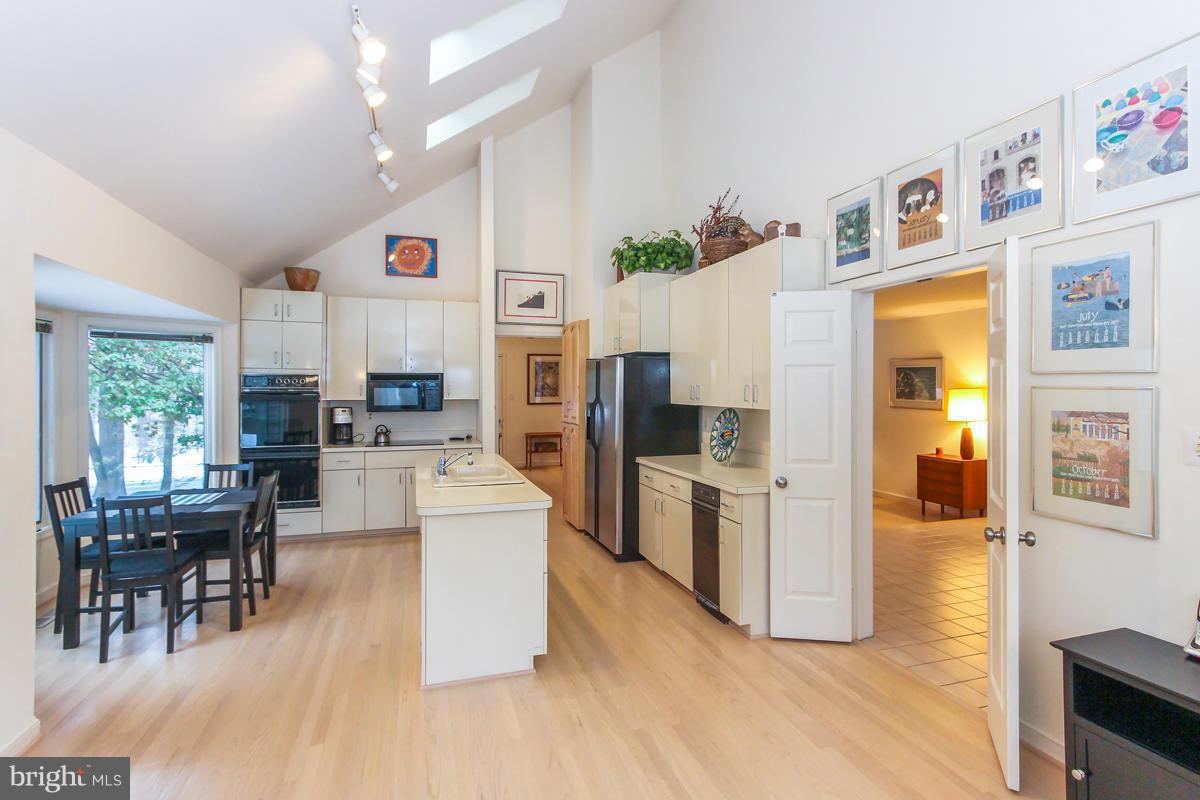 1587 Regatta Lane Reston, VA 20194 - Photo 9 of 30 a kitchen with stainless steel appliances a refrigerator a stove top oven a sink dishwasher and white cabinets with wooden floor