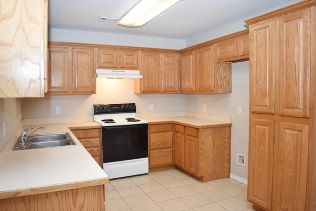 760-764 Stribling Circle Azle, TX 76020 - Photo 12 of 18 Kitchen with white electric range, light countertops, and light tile patterned floors