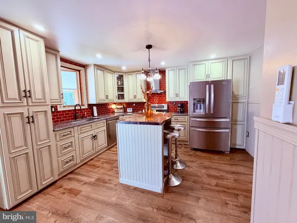 a room with lots of white furniture a chandelier and a wooden floor