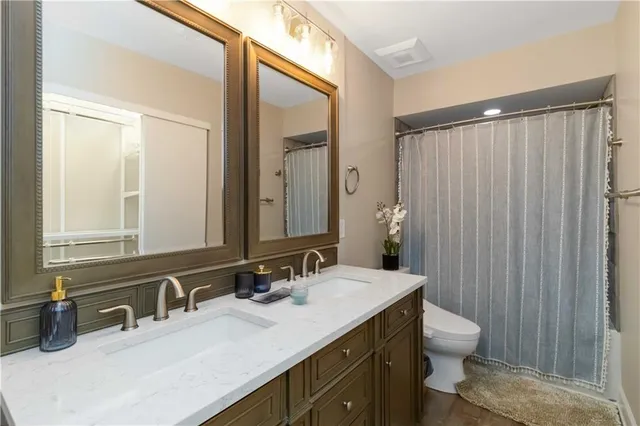 a bathroom with a double vanity sink toilet and a mirror