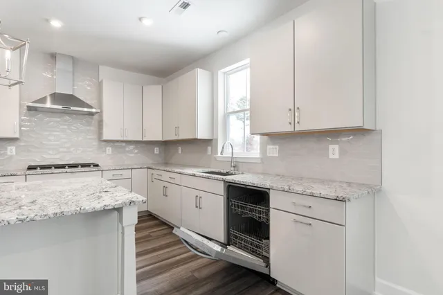 a kitchen with stainless steel appliances granite countertop a stove a sink and white cabinets
