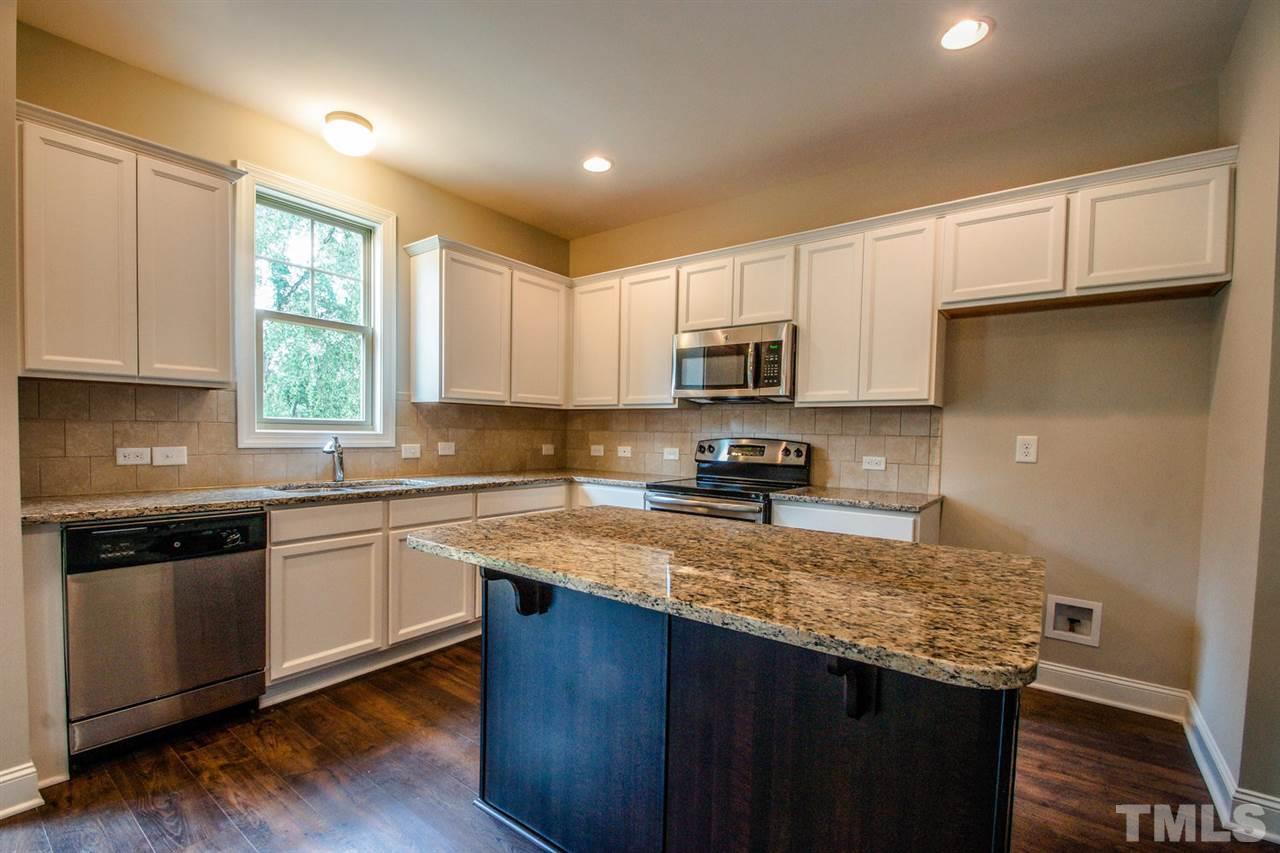1216 Silver Farm Road Raleigh, NC 27603 - Photo 3 of 25 a kitchen with kitchen island granite countertop a stove sink and cabinets