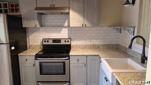 a kitchen with granite countertop a sink stainless steel appliances and cabinets