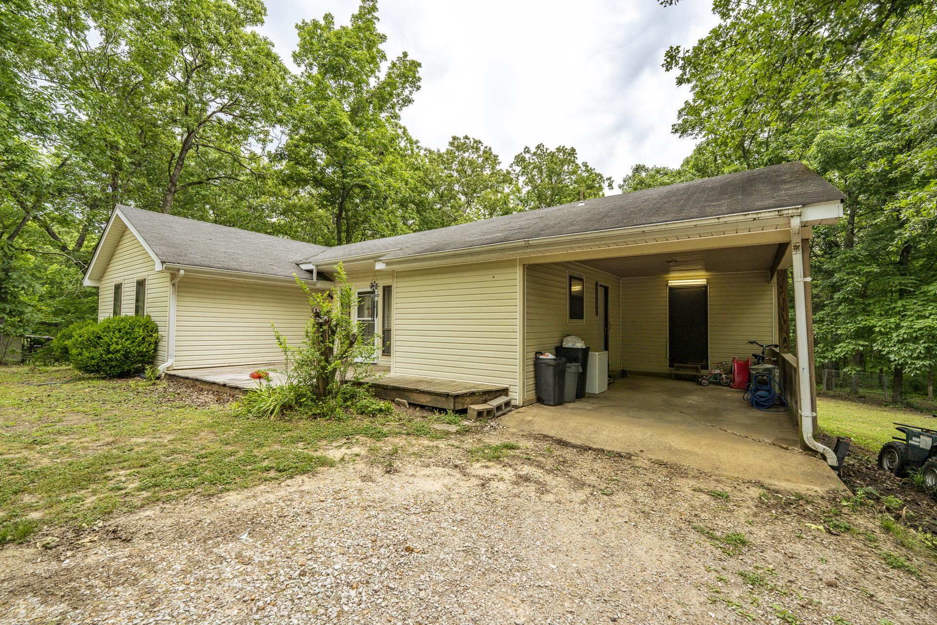 259 Oakview Drive Adamsville, TN 38310 - Photo 2 of 32 Exterior featuring cream-colored siding, a covered carport, and a gravel driveway