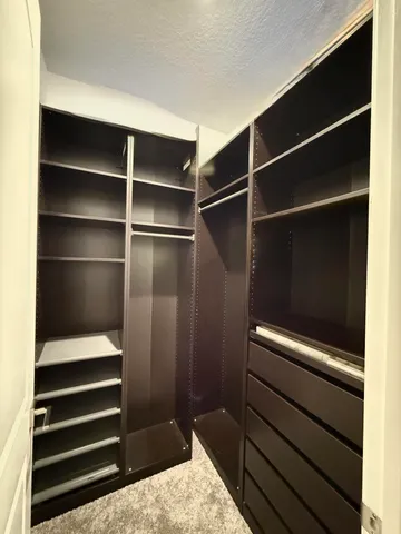 a view of walk in closet with clothes and shoes