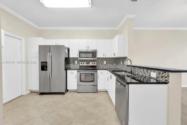 a kitchen with stainless steel appliances white cabinets and a refrigerator