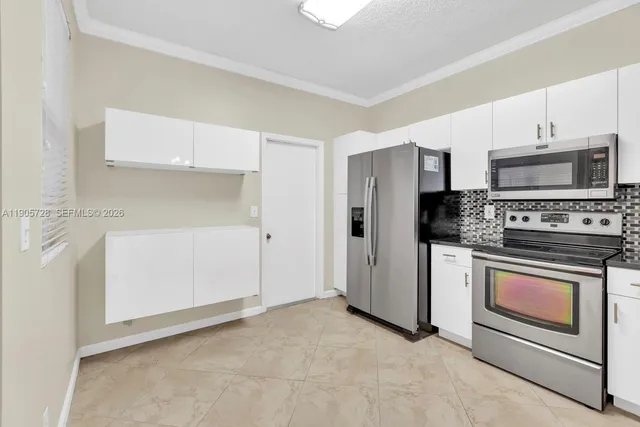 a kitchen with granite countertop white cabinets white stainless steel appliances and a sink