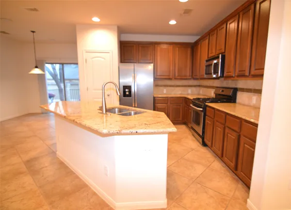 a kitchen with stainless steel appliances granite countertop a sink and a refrigerator