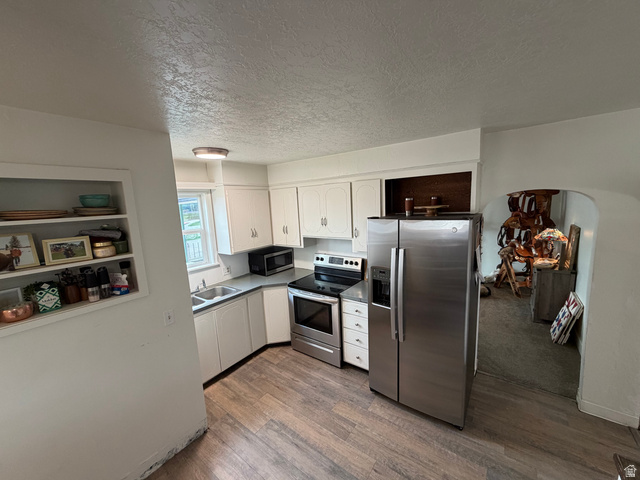 108 West 2nd South Grace, ID 83241 - Photo 6 of 20 Kitchen featuring stainless steel appliances, white cabinets, arched walkways, dark wood-style floors and new flooring.
