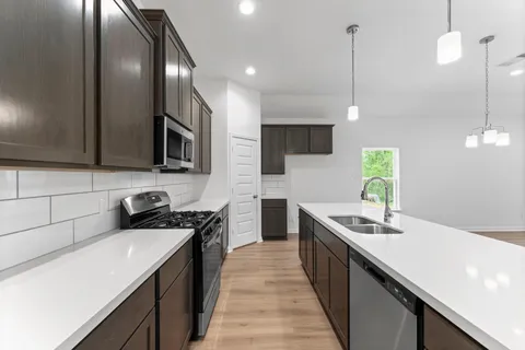 a kitchen with stainless steel appliances a sink a stove top oven a counter space and cabinets