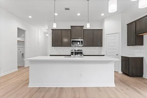 a large kitchen with a large counter top a sink stainless steel appliances and cabinets