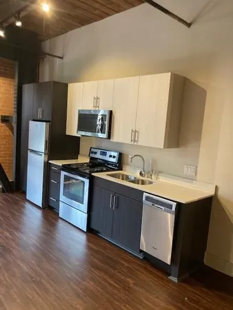 a kitchen with stainless steel appliances a sink dishwasher a refrigerator a stove and wooden floor