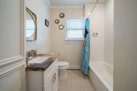 a bathroom with a granite countertop sink a toilet a mirror and bathtub