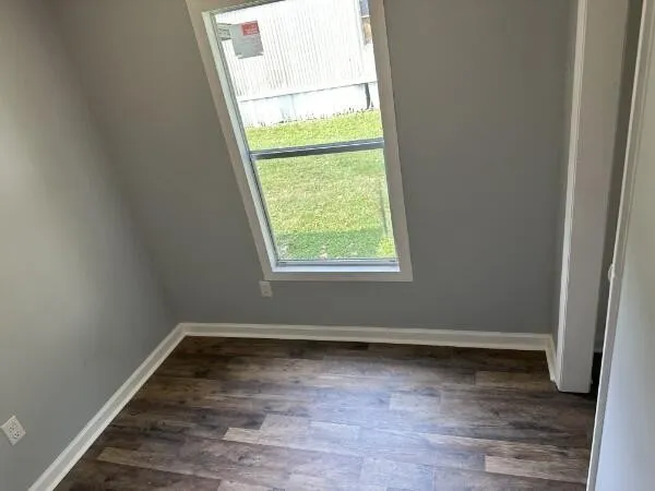 an empty room with wooden floor and window