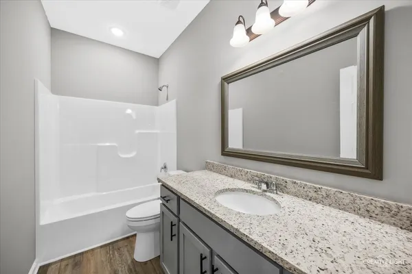 a bathroom with a granite countertop sink a toilet a mirror and shower