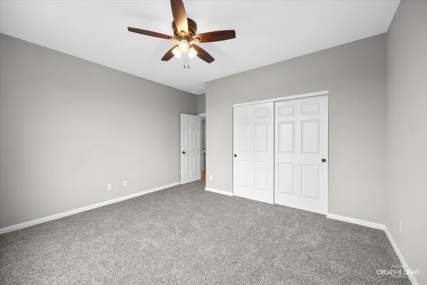 an empty room with a ceiling fan and carpet