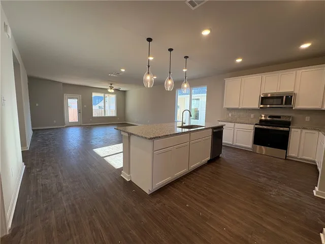 a kitchen with stainless steel appliances kitchen island granite countertop wooden floors and white cabinets