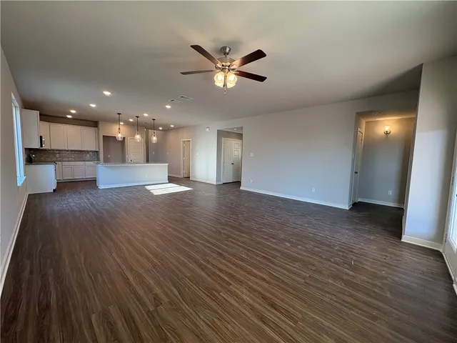 a view of a big room with wooden floor a ceiling fan and windows
