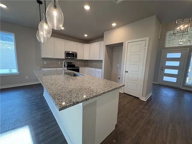 a kitchen with granite countertop a stove and wooden floor