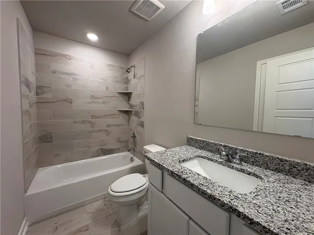 a bathroom with a granite countertop sink a toilet and bathtub
