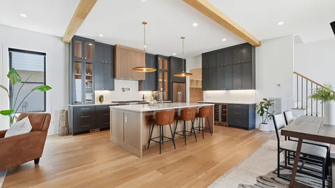 a large kitchen with cabinets wooden floor stainless steel appliances and dining table