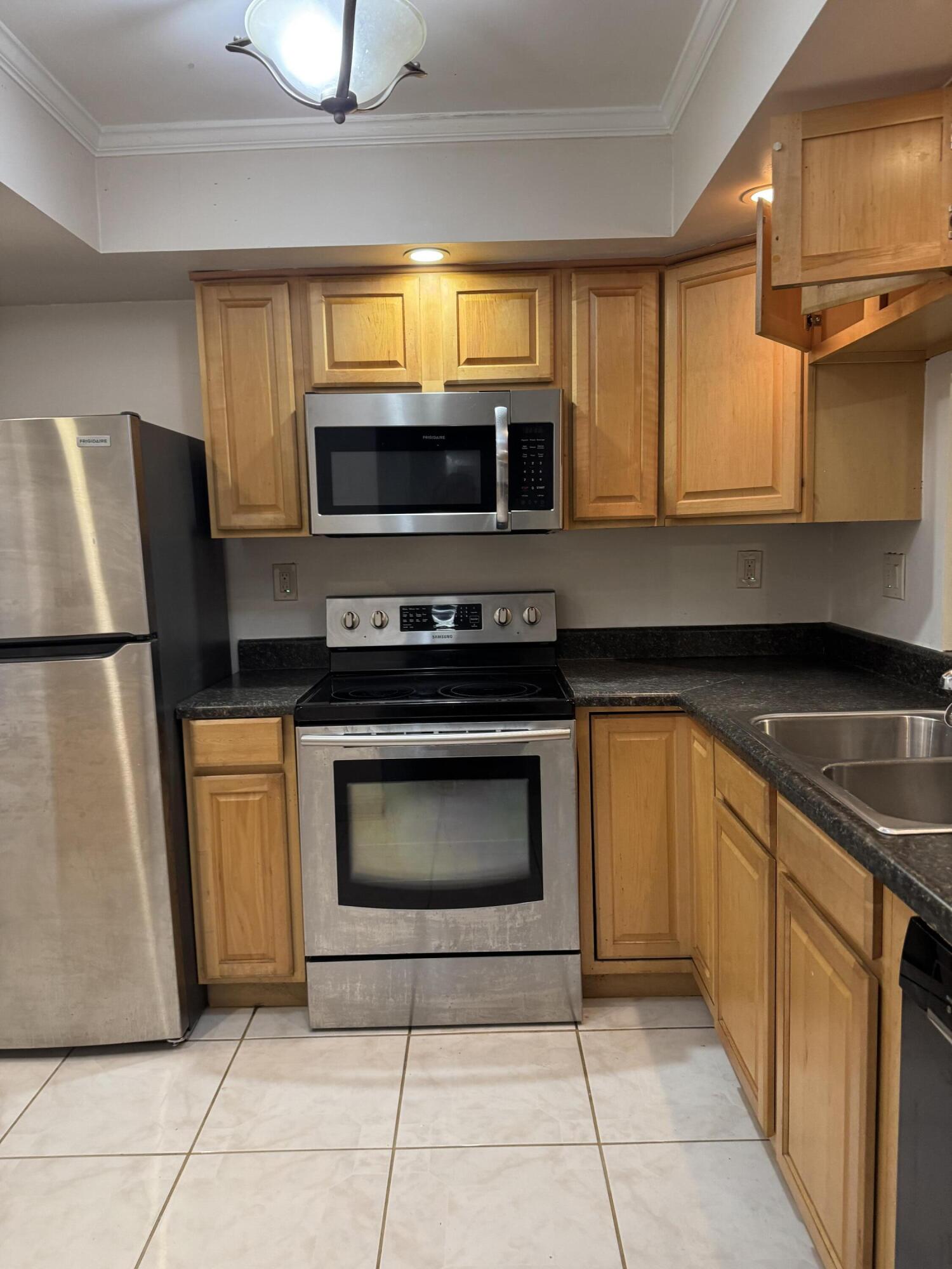 9374 Southwest 3rd Street, Unit 718 Boca Raton, FL 33428 - Photo 3 of 5 a kitchen with granite countertop a refrigerator and a stove top oven