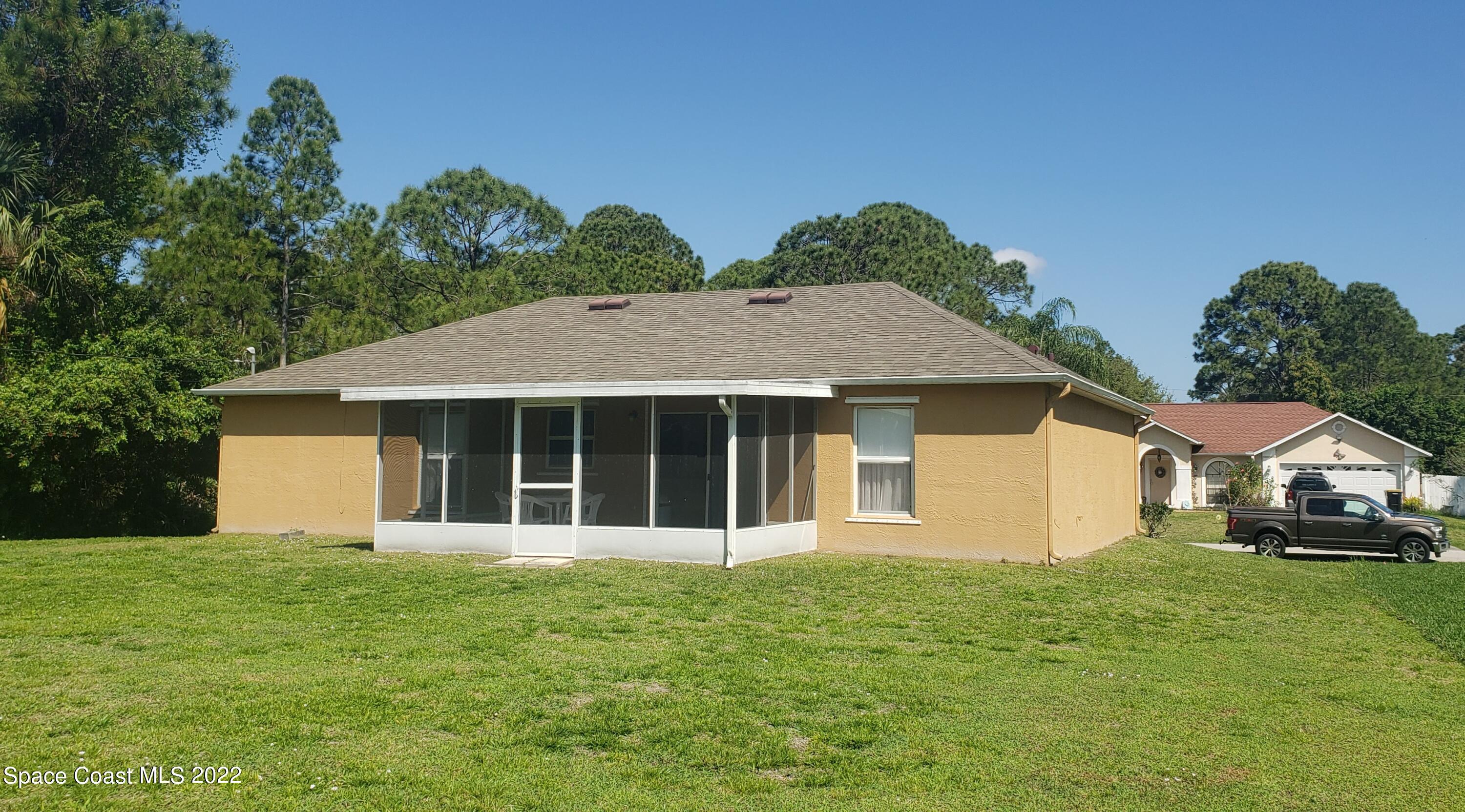 1260 Daton Road Southwest Palm Bay, FL 32908 - Photo 17 of 17 a view of a white house with a small yard and large tree