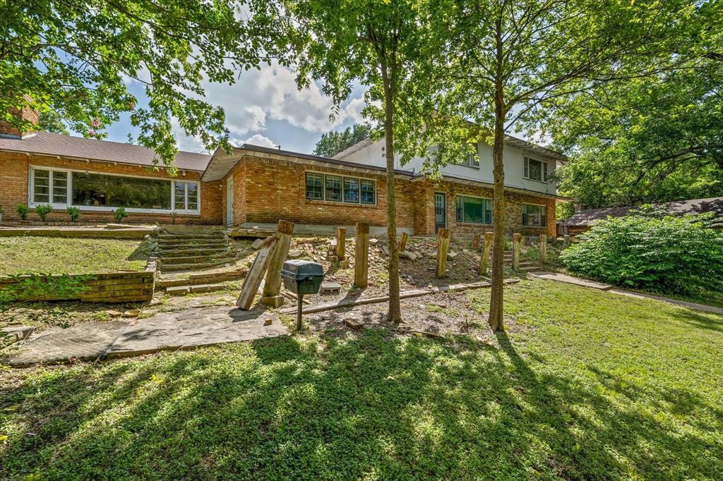 421 Rice Avenue Waco, TX 76708 - Photo 3 of 22 Expansive backyard oasis featuring mature shade trees, manicured lawn, wooden pergola structure, and stone patio with stepped entry
