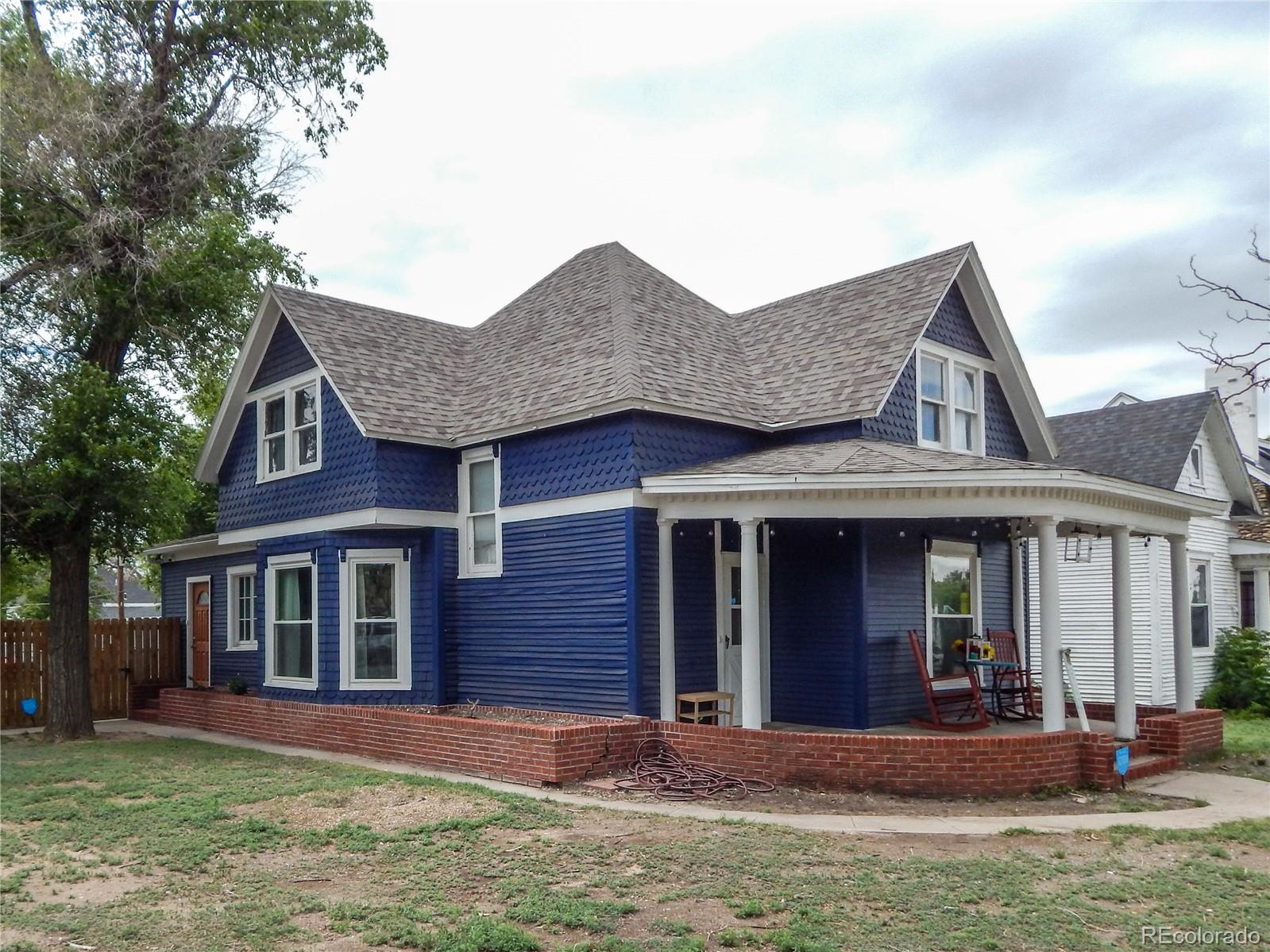 910 South Main Street Lamar, CO 81052 - Photo 2 of 37 a view of a brick house with many windows and a yard with plants and large trees