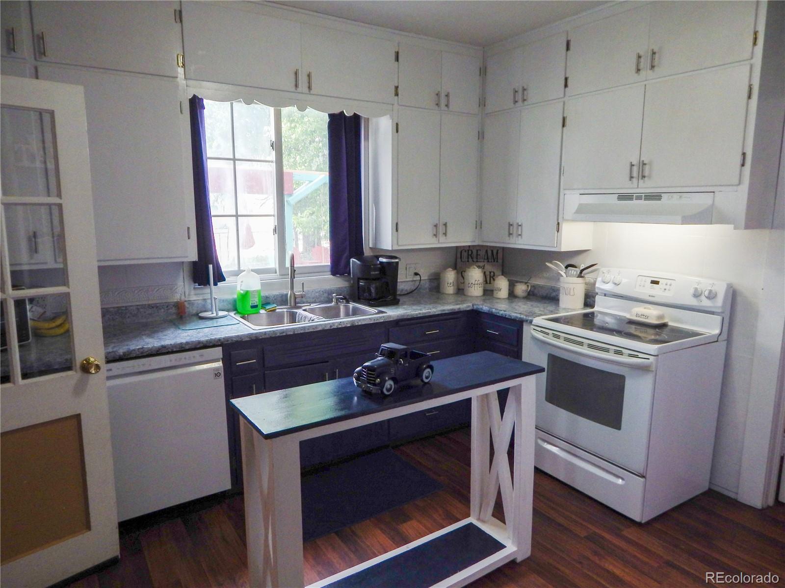 910 South Main Street Lamar, CO 81052 - Photo 8 of 37 a kitchen with granite countertop a sink a stove and wooden cabinets