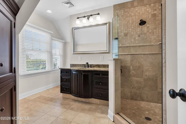 a bathroom with a granite countertop sink a vanity and a shower