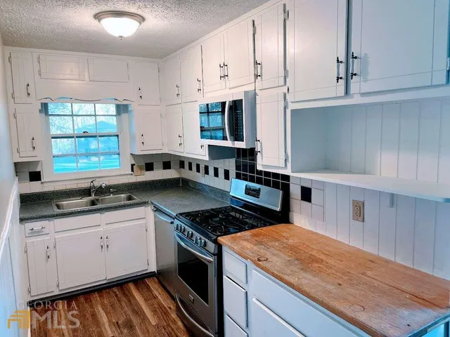 a kitchen with stainless steel appliances granite countertop a stove a sink and a microwave
