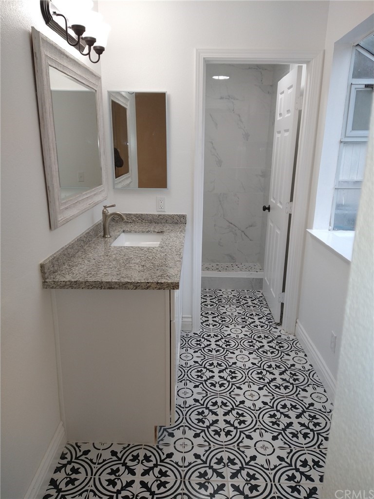 a bathroom with a granite countertop sink a mirror and shower